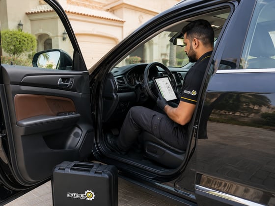 Autofay technician visually inspecting brake area through the wheel without removing the tire during brake inspection in UAE