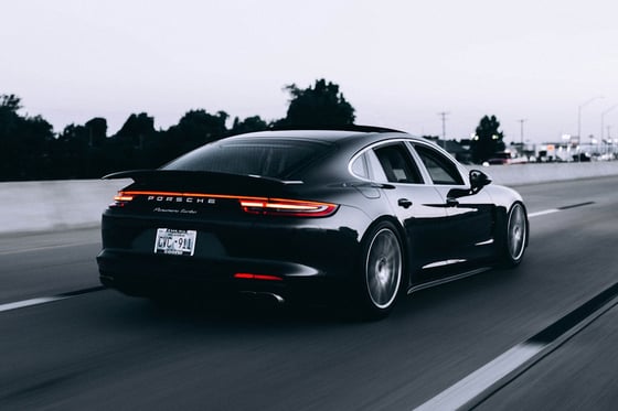 Inspector pressing brake and gas pedals checking feel, foot on pedal, seatbelt buckled, bright interior with Dubai visible through windshield