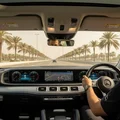 Cockpit view from passenger seat, inspector checking mirrors during lane change, speedometer at 80kmh, Dubai palm-lined highway, bright afternoon