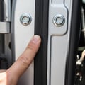 Close-up of inspector checking driver seat leather for wear and cracks, finger pressing on bolster, bright daylight through window
