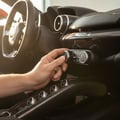 Close-up of inspector's hand adjusting dual-zone climate control dial, switching between cool and heat, bright center console from open door