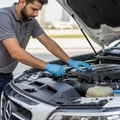Inspector standing beside open hood listening to engine idle, hand on fender, clean engine bay running, outdoor Dubai morning
