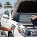 Silver luxury SUV on portable lift outdoors in Dubai, inspector with tablet checking underneath while hood is open showing engine bay, full 360 inspection scene, bright daylight