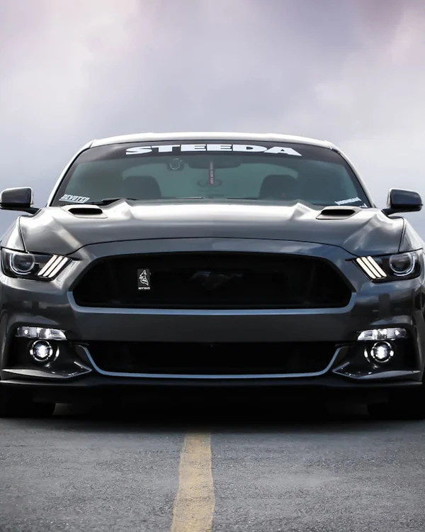 Inspector holding digital paint thickness gauge pressed flat against white SUV hood, close-up showing gauge display reading 120 microns, car parked outdoors in bright Dubai sunlight