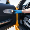 Inspector adjusting power seat forward using door panel controls, seat motor humming, memory button 1 lit, bright interior from open door