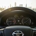 Inspector sitting in driver seat pressing push-start button, finger on button, dashboard gauges lighting up, morning light through windshield
