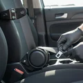 Inspector checking windshield camera calibration, reaching up to sensor housing behind rearview mirror, bright interior daylight