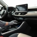 Inspector placing phone on wireless charging pad in center console, Bluetooth icon visible on touchscreen above, bright Dubai daylight through windows